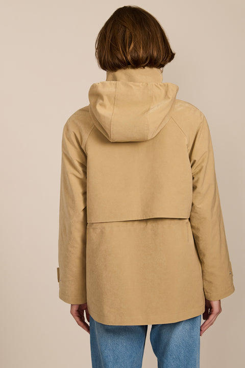 Women's hooded raincoat with drawstring waist, storm flap, side pockets and adjustable cuffs.