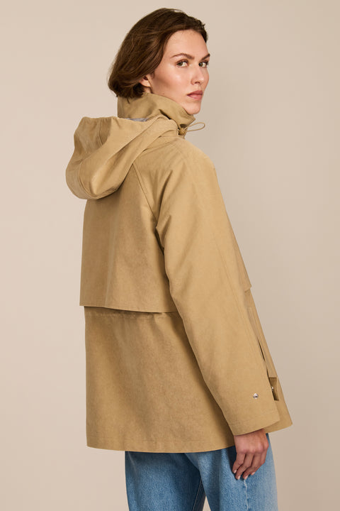 Women's hooded raincoat with drawstring waist, storm flap, side pockets and adjustable cuffs.