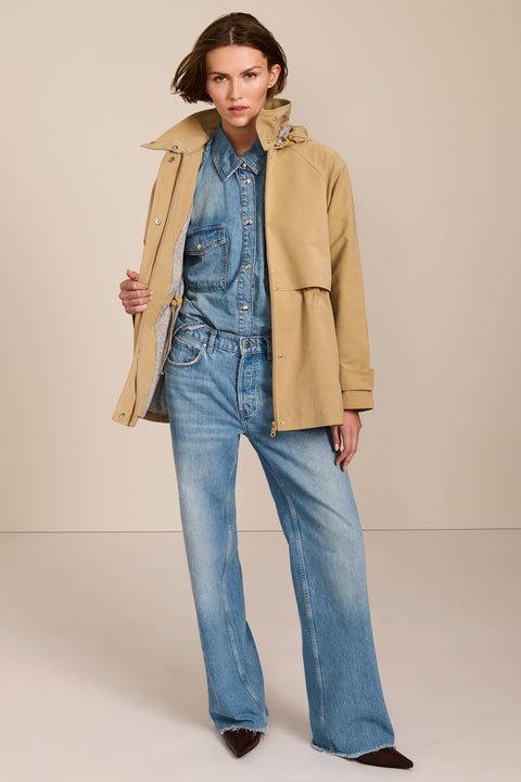 Women's hooded raincoat with drawstring waist, storm flap, side pockets and adjustable cuffs.