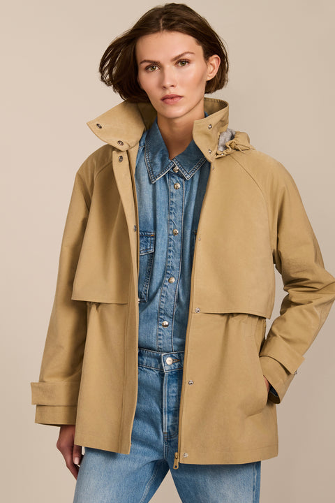 Women's hooded raincoat with drawstring waist, storm flap, side pockets and adjustable cuffs.