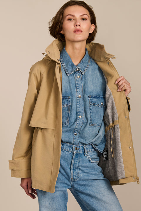 Women's hooded raincoat with drawstring waist, storm flap, side pockets and adjustable cuffs.