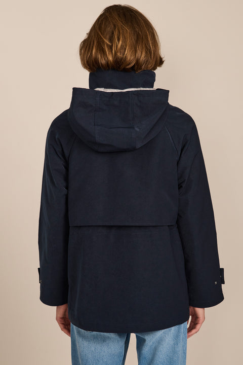 Women's hooded raincoat with drawstring waist, storm flap, side pockets and adjustable cuffs.