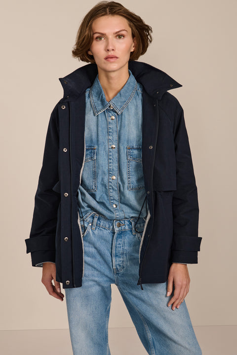 Women's hooded raincoat with drawstring waist, storm flap, side pockets and adjustable cuffs.