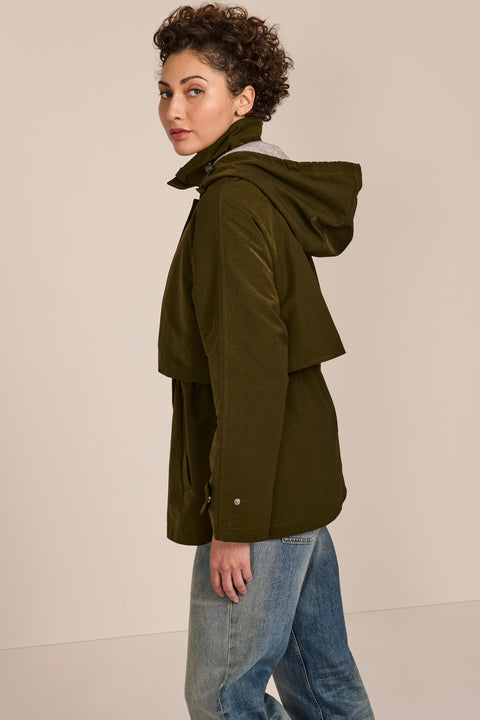 Women's hooded raincoat with drawstring waist, storm flap, side pockets and adjustable cuffs.