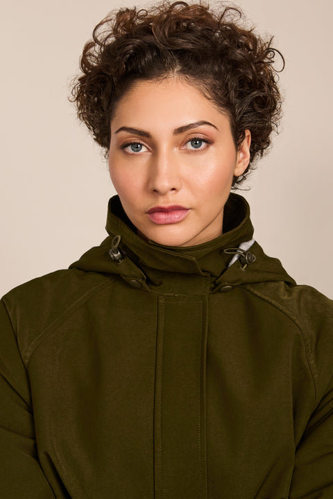 Women's hooded raincoat with drawstring waist, storm flap, side pockets and adjustable cuffs.