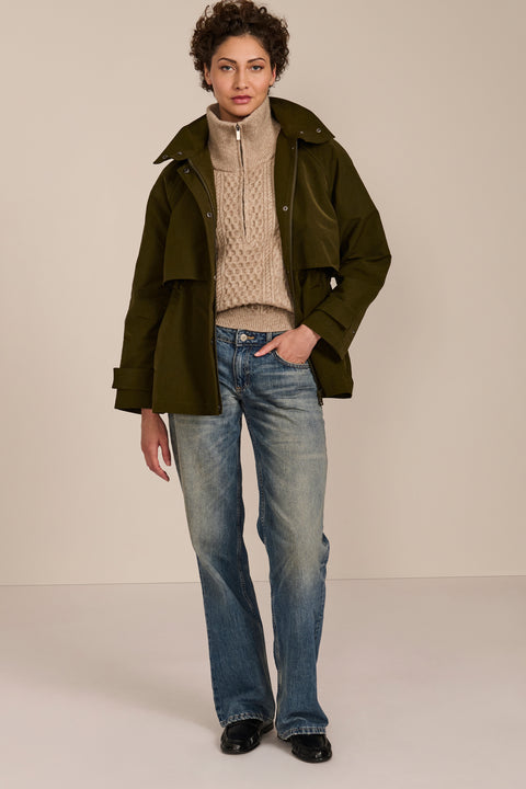 Women's hooded raincoat with drawstring waist, storm flap, side pockets and adjustable cuffs.