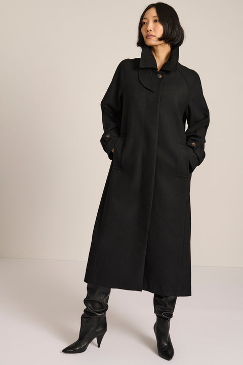 women's long wool coat in black with a sculptural convertible collar, long relaxed silhouette and button-tab cuffs.