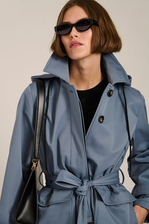 Women's belted raincoat with removable hood and water-repellent finish.