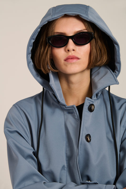 Women's belted raincoat with removable hood and water-repellent finish.
