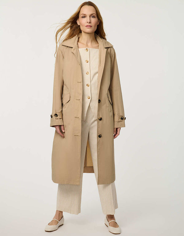 Women’s lightweight utility trench coat with belted waist, flap pockets, and roll-away hood tucked into the collar.
