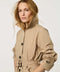 Women’s lightweight utility trench coat with belted waist, flap pockets, and roll-away hood tucked into the collar.