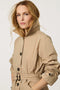 Women’s lightweight utility trench coat with belted waist, flap pockets, and roll-away hood tucked into the collar.