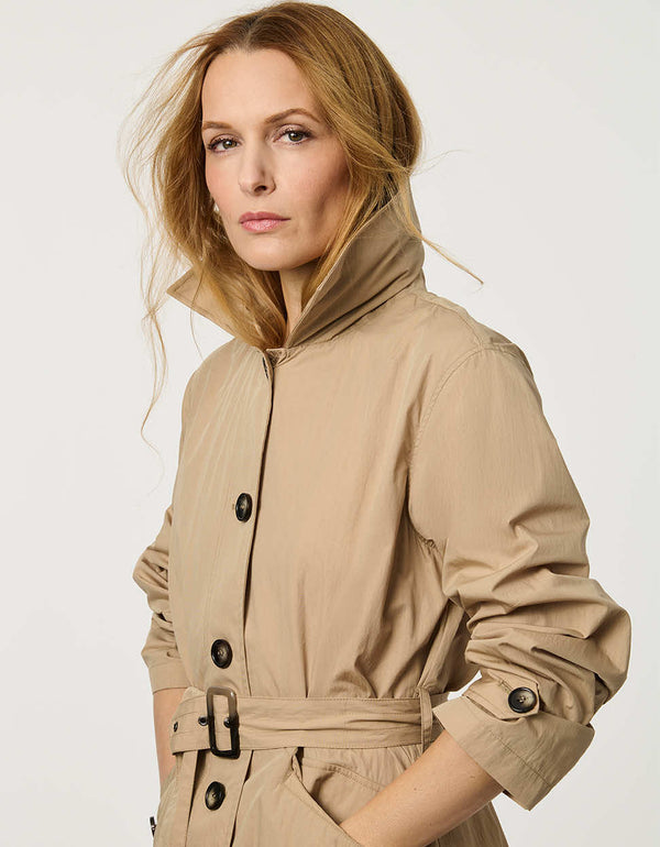 Women’s lightweight utility trench coat with belted waist, flap pockets, and roll-away hood tucked into the collar.