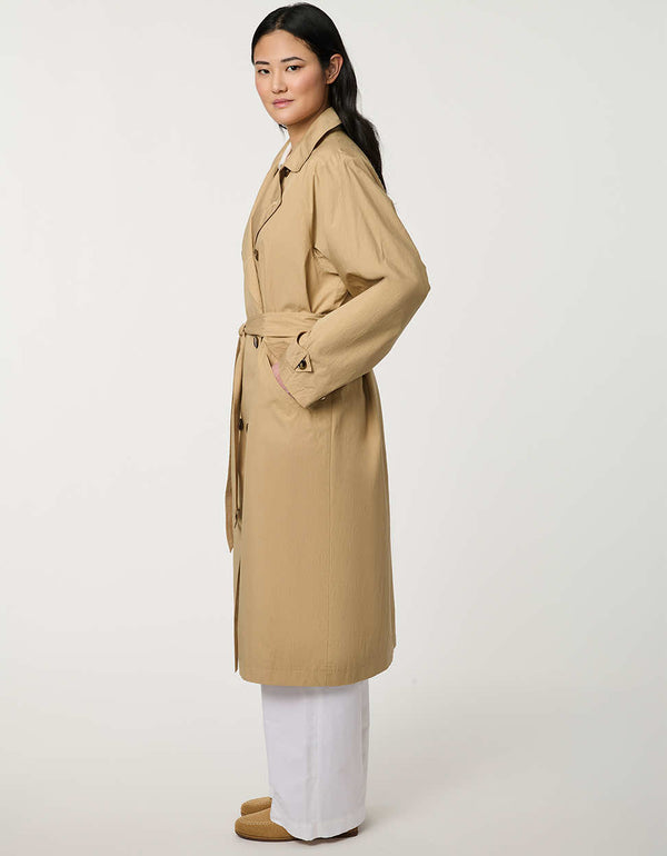 Women’s double-breasted trench coat with belted waist, cuff tabs, and striped interior lining.