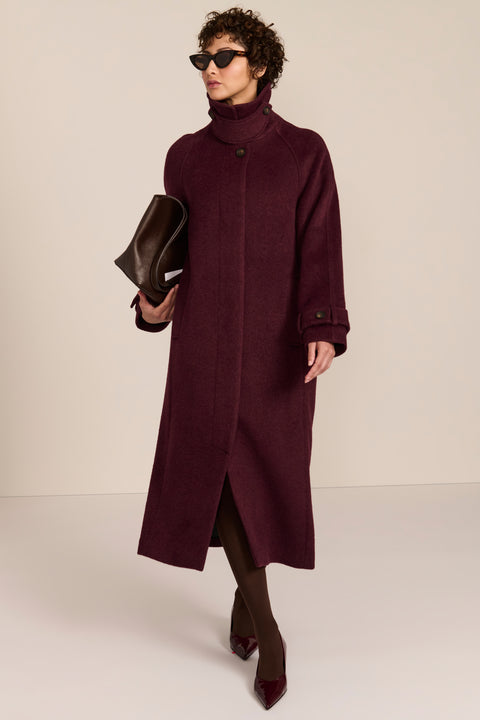Women's long wool coat featuring a sculptural stand collar, concealed front closure, patch pockets, and button-tab cuffs.