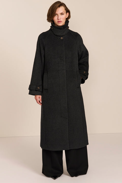 Women's long wool coat featuring a sculptural stand collar, concealed front closure, patch pockets, and button-tab cuffs.