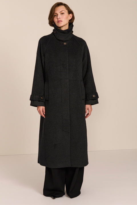 Women's long wool coat featuring a sculptural stand collar, concealed front closure, patch pockets, and button-tab cuffs.