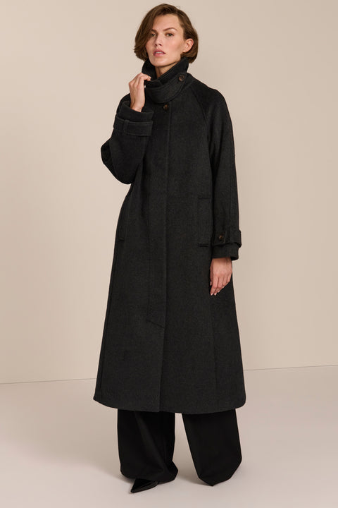 Women's long wool coat featuring a sculptural stand collar, concealed front closure, patch pockets, and button-tab cuffs.