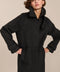 Women's long wool coat featuring a sculptural stand collar, concealed front closure, patch pockets, and button-tab cuffs.
