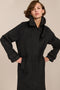 Women's long wool coat featuring a sculptural stand collar, concealed front closure, patch pockets, and button-tab cuffs.