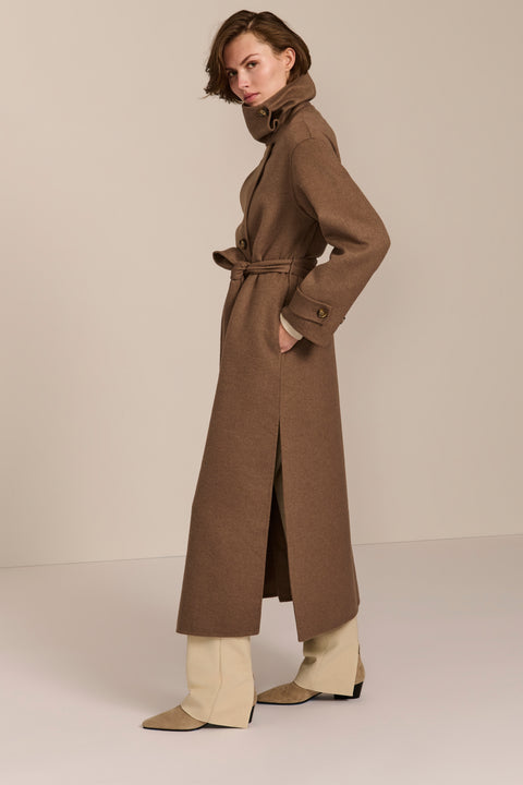 Women's long belted wool coat featuring a high stand collar, asymmetric button closure, wide cuffs and side slits.