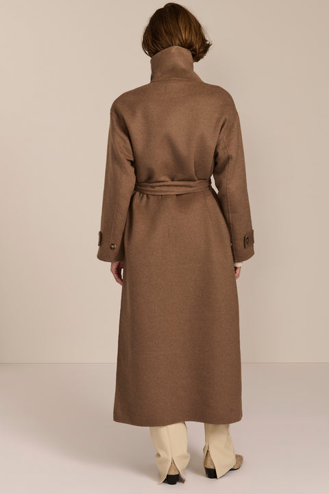 Women's long belted wool coat featuring a high stand collar, asymmetric button closure, wide cuffs and side slits.