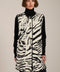 Long Bengal-inspired faux fur vest with collarless silhouette, faux leather trim and elongated fit.