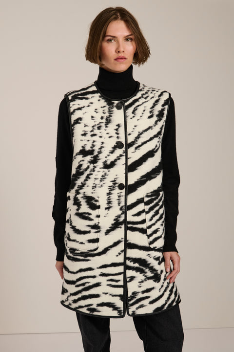Long Bengal-inspired faux fur vest with collarless silhouette, faux leather trim and elongated fit.