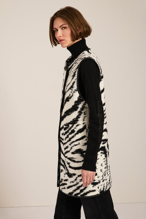 Long Bengal-inspired faux fur vest with collarless silhouette, faux leather trim and elongated fit.