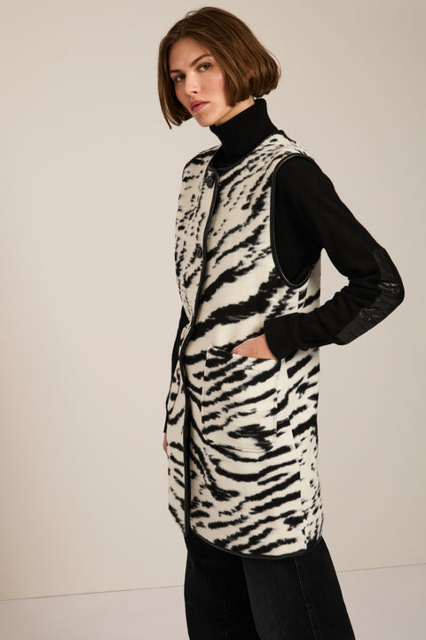Long Bengal-inspired faux fur vest with collarless silhouette, faux leather trim and elongated fit.