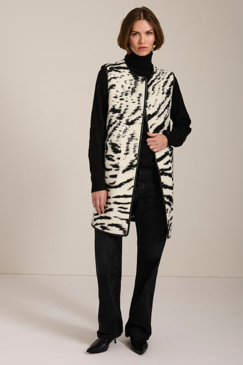 Long Bengal-inspired faux fur vest with collarless silhouette, faux leather trim and elongated fit.