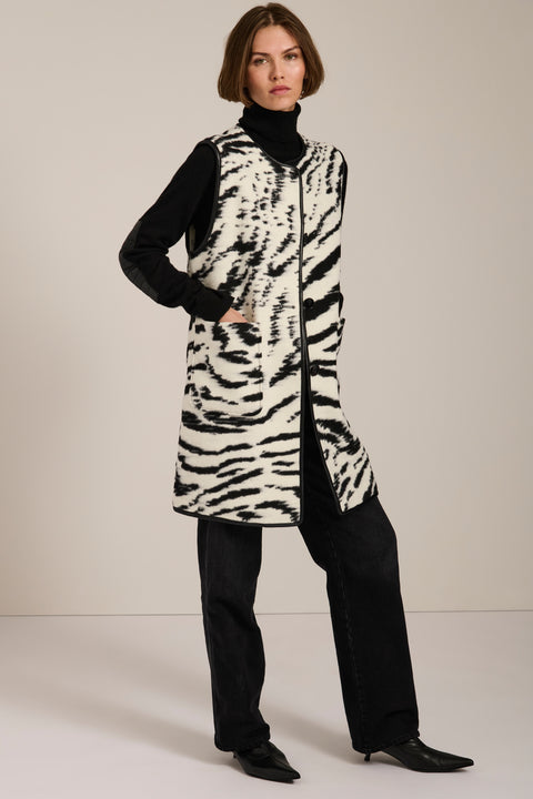 Long Bengal-inspired faux fur vest with collarless silhouette, faux leather trim and elongated fit.