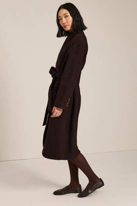 Belted bouclé wrap coat with rounded shawl collar, textured fabric and modern wrap silhouette.