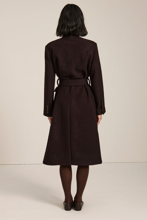 Belted bouclé wrap coat with rounded shawl collar, textured fabric and modern wrap silhouette.