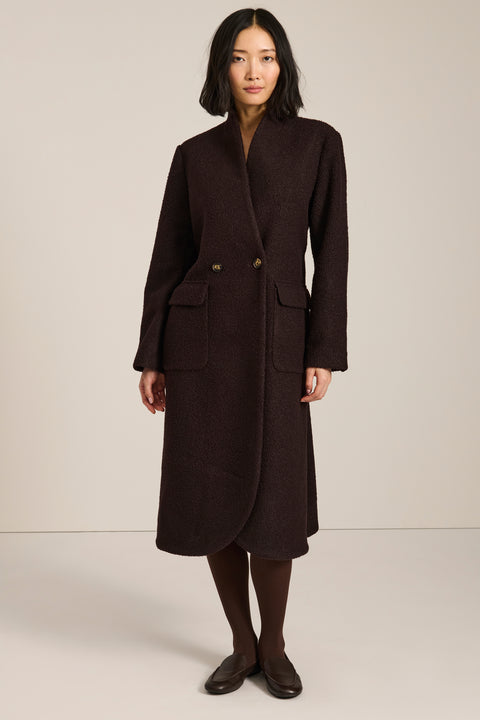 Belted bouclé wrap coat with rounded shawl collar, textured fabric and modern wrap silhouette.