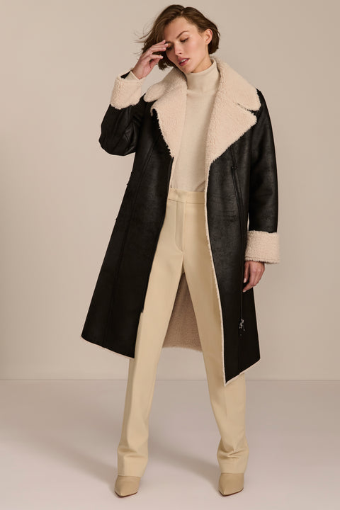 women's black faux shearling belted coat featuring ivory contrast trim, oversized notched collar, zip-front closure and zip pockets.