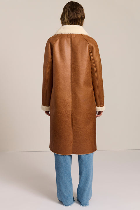 women's faux shearling coat featuring ivory contrast trim, an oversized notched collar, double-breasted button closure and patch pockets.
