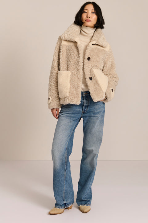 women's cream mixed-media teddy jacket with contrasting faux shearling textures, oversized patch pockets, button-front closure, and a plush stand collar.