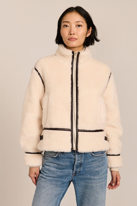 women's ivory sherpa jacket featuring a stand collar, contrast trim, zip-front closure and adjustable buckle tabs at the sides.