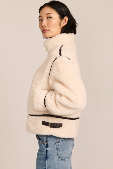 women's ivory sherpa jacket featuring a stand collar, contrast trim, zip-front closure and adjustable buckle tabs at the sides.