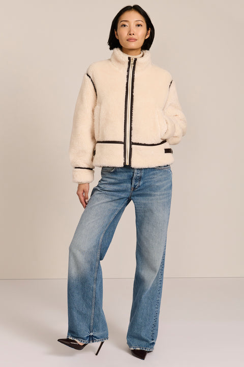 women's ivory sherpa jacket featuring a stand collar, contrast trim, zip-front closure and adjustable buckle tabs at the sides.