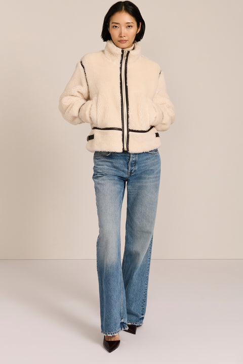 women's ivory sherpa jacket featuring a stand collar, contrast trim, zip-front closure and adjustable buckle tabs at the sides.