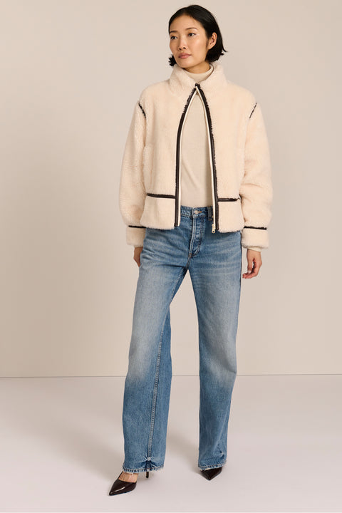 women's ivory sherpa jacket featuring a stand collar, contrast trim, zip-front closure and adjustable buckle tabs at the sides.