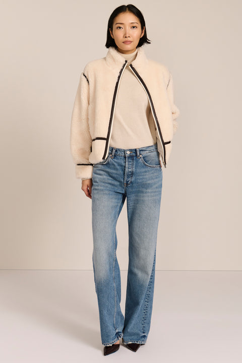 women's ivory sherpa jacket featuring a stand collar, contrast trim, zip-front closure and adjustable buckle tabs at the sides.