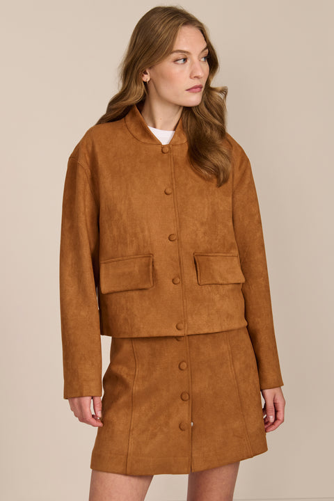 women's camel faux suede bomber jacket with a tonal snap front and flap pockets, styled with the coordinating mini skirt.