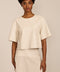 women's ivory faux leather short-sleeve top featuring a crew neckline, relaxed cropped silhouette and perforated chest pocket.