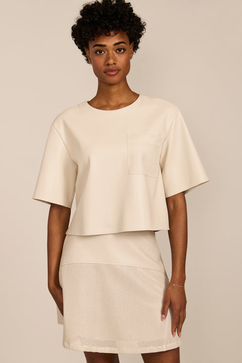 women's ivory faux leather short-sleeve top featuring a crew neckline, relaxed cropped silhouette and perforated chest pocket.
