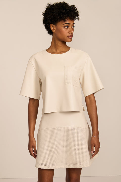 women's ivory faux leather short-sleeve top featuring a crew neckline, relaxed cropped silhouette and perforated chest pocket.