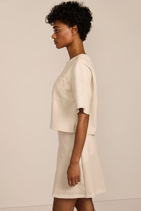 women's ivory faux leather short-sleeve top featuring a crew neckline, relaxed cropped silhouette and perforated chest pocket.