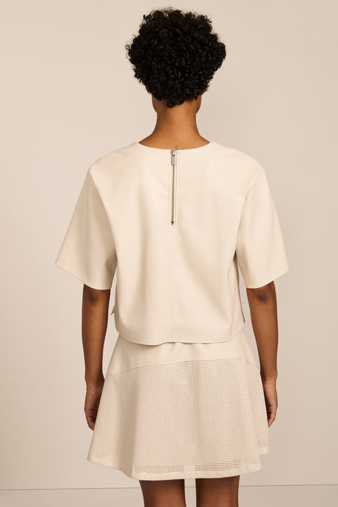 women's ivory faux leather short-sleeve top featuring a crew neckline, relaxed cropped silhouette and perforated chest pocket.